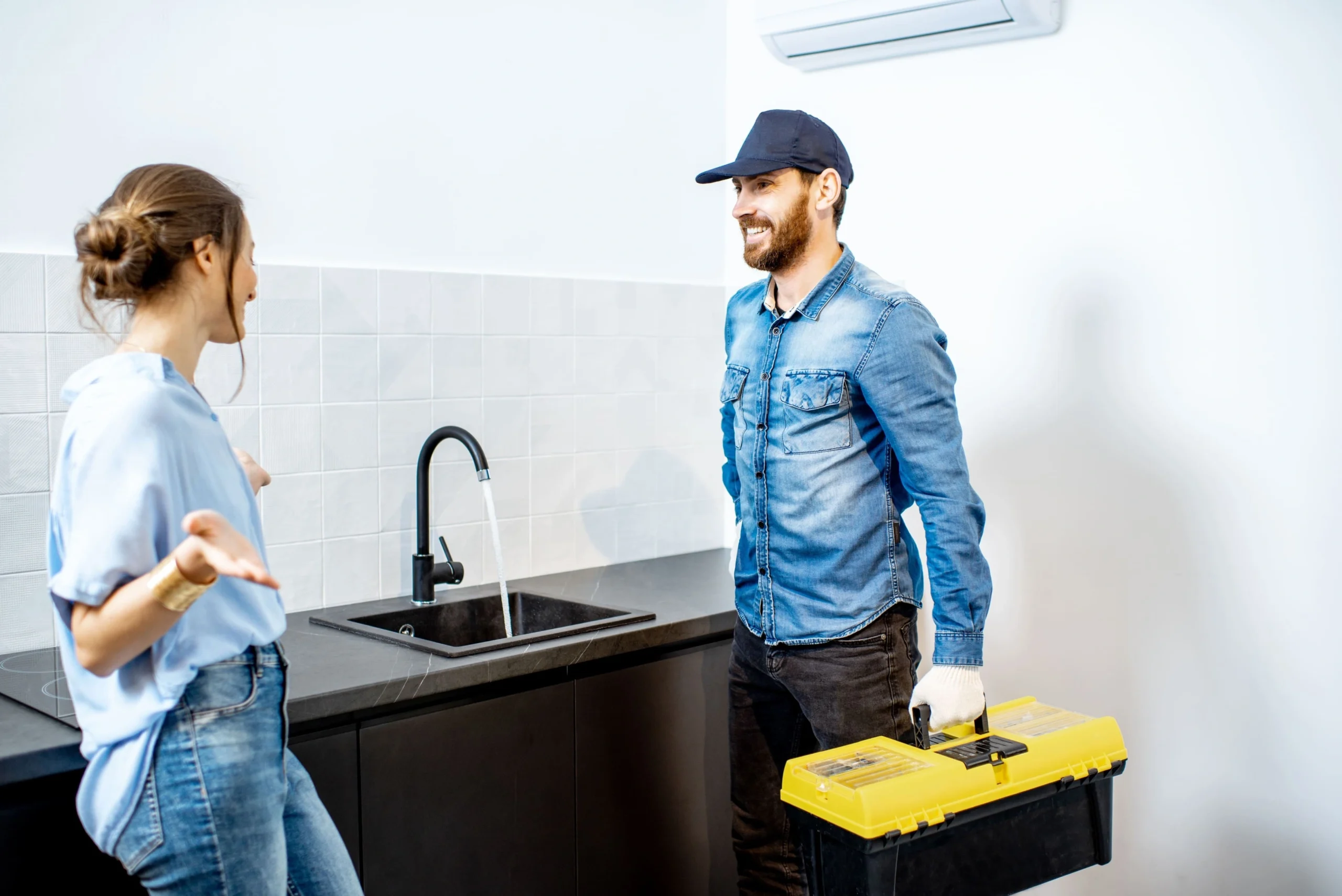 Plombier Bruxelles réparant une fuite d'eau sous évier dans une cuisine moderne, service rapide et efficace le jour même