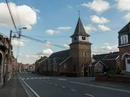 Plombier Oupeye devant l'église Saint-Remy, architecture ancienne entourée de rues pavées et de maisons en briques typiques