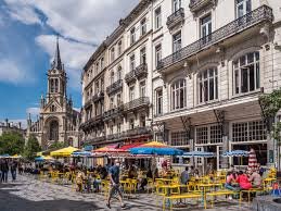 Plombier Saint Gilles camion devant église historique rue pavée typique avec boutiques charmantes et passants décontractés